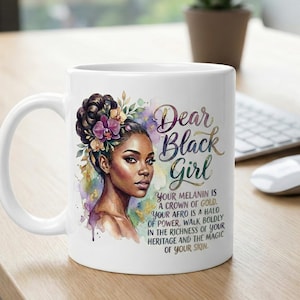 May include: White ceramic mug featuring a watercolor illustration of a Black woman with flowers in her hair. The mug has the text "Dear Black Girl" and an inspirational message. The mug is on a wooden surface.