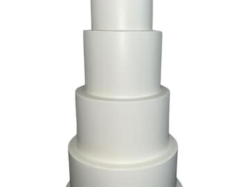 May include: A four-tier white wedding cake with smooth frosting. The cake is on a white cake board.