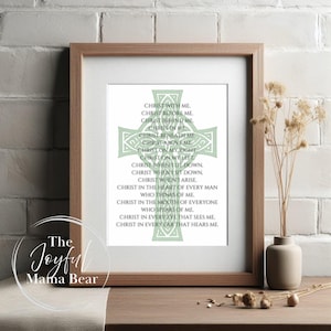 May include: A framed print with a light green cross design and text. The text includes phrases such as "Christ with me" and "Christ in me." The frame is a light brown colour. The Joyful Mama Bear logo is in the lower left corner.