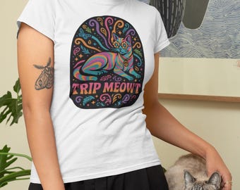 May include: White t-shirt with a colorful graphic of a psychedelic cat wearing glasses and the text "TRIP MEOWT". The cat design features rainbow colors and swirling patterns. The shirt is a casual style.