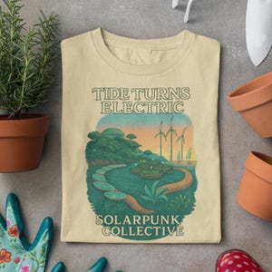 May include: Cream-colored t-shirt with a graphic featuring a landscape with wind turbines, water, and the text "Tide Turns Electric" and "Solarpunk Collective". The design is in shades of green, blue, and orange.