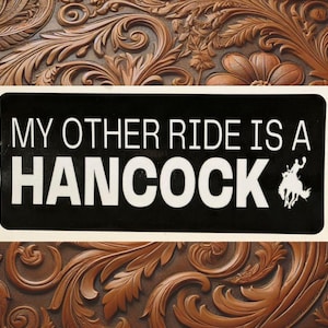 May include: Black and white sticker with the text "My other ride is a Hancock" and a silhouette of a person riding a horse.