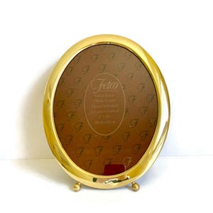May include: A gold oval-shaped solid brass photo frame with a stand. The frame is hand polished and lacquer coated. It is 8x10 inches or 20 cm x 25 cm.