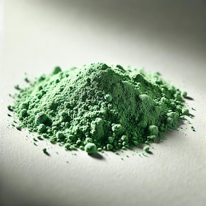 Può includere: Un mucchio di polvere verde su una superficie bianca. La polvere è finemente macinata e ha una consistenza uniforme.