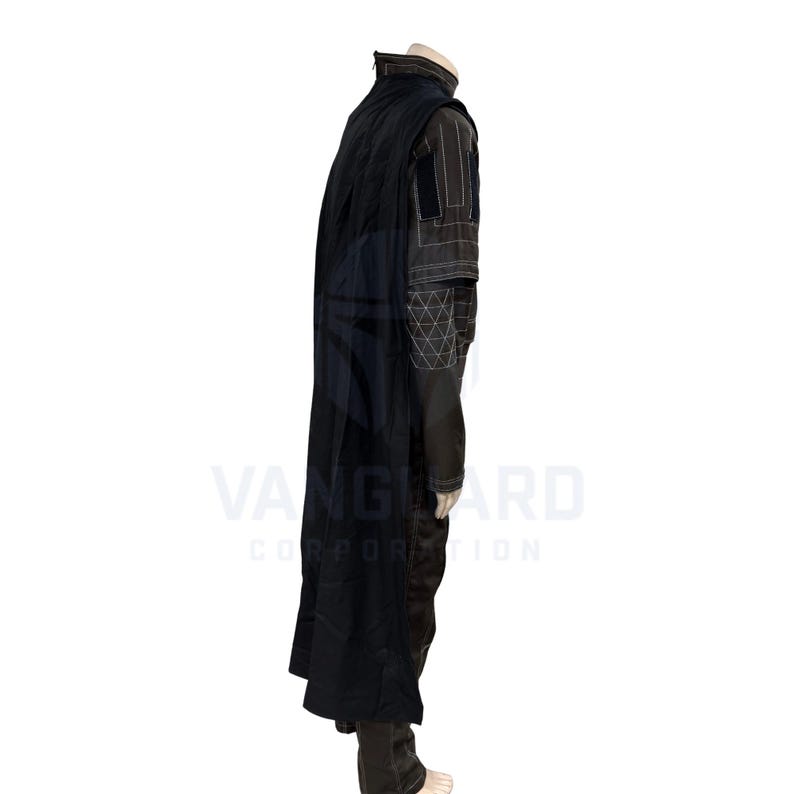 May include: A black costume with a long cape. The outfit includes a high-collared jacket with geometric and striped detailing, and dark pants. The costume is displayed on a mannequin.