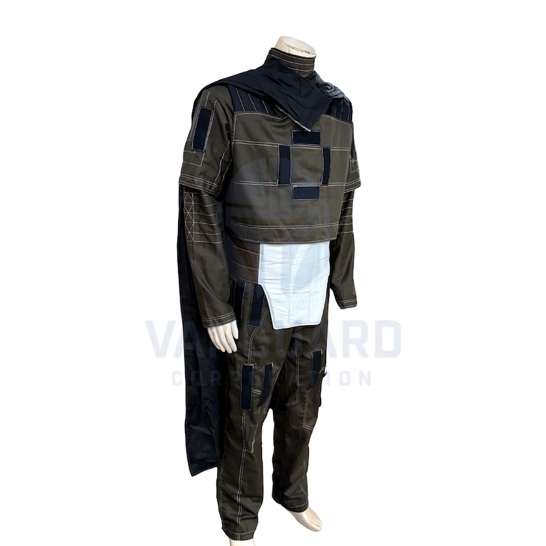 May include: A brown and black costume with a cape, jacket, and pants. The jacket has black patches and white stitching. The costume includes a black cape and a white panel on the front. The outfit is displayed on a mannequin.