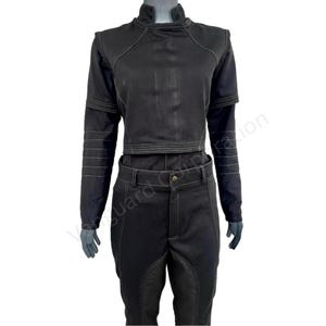 Puede incluir: Una blusa negra de manga larga con cuello alto y costuras blancas. La blusa es corta y tiene una silueta ajustada. Los pantalones son negros con costuras blancas y pierna recta.