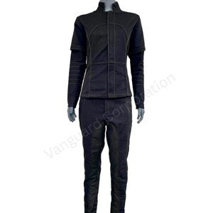 Puede incluir: Un mono negro con una chaqueta de cuello. La chaqueta tiene una cremallera y detalles de costura amarilla contrastantes. El pantal&oacute;n tiene un ajuste delgado y un panel negro contrastante en las rodillas.