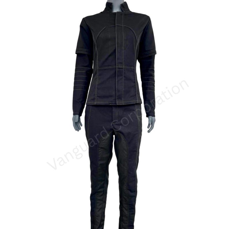 Puede incluir: Un mono negro con una chaqueta de cuello. La chaqueta tiene una cremallera y detalles de costura amarilla contrastantes. El pantal&oacute;n tiene un ajuste delgado y un panel negro contrastante en las rodillas.