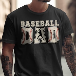 May include: Black t-shirt with the words "BASEBALL DAD" in a distressed, vintage style. The word "BASEBALL" is above "DAD". The letter "D" in "DAD" features a baseball with red stitching, and a silhouette of a baseball player.