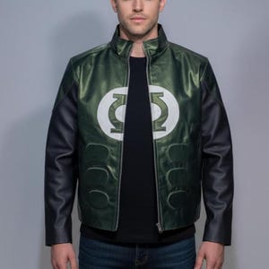 May include: Green and black leather jacket with a white emblem on the chest. The jacket has a stand-up collar, a zipper closure, and black sleeves. The emblem is a stylized white circle with a green design inside.