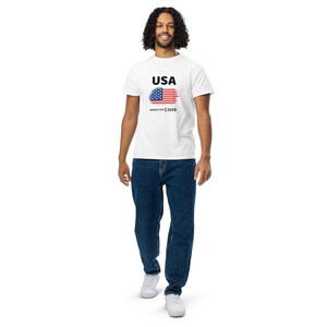 May include: White t-shirt with a graphic of the USA flag and the text "USA World Cup 2026".