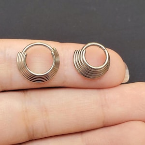 May include: Two silver hoop earrings with a layered design. Each hoop has five layers of metal.