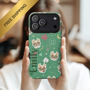May include: Green phone case with a Taurus zodiac design, featuring cartoon bulls, flowers, and stars. The name "Emily" is printed vertically on the case. The case has a black camera module and is held by a person.