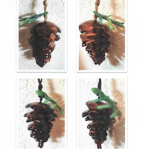 Peut inclure: Quatre images montrant comment réaliser des pommes de pin en verre fusionné. Chaque image montre une étape différente du processus, la dernière image montrant une pomme de pin terminée.