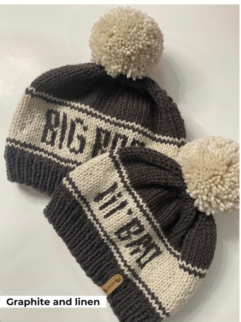Puede incluir: Dos gorros de punto con pompones. El gorro m&aacute;s grande es gris con rayas blancas y el texto "BIG MOM" en blanco. El gorro m&aacute;s peque&ntilde;o es gris con rayas blancas y el texto "MY BABY" en blanco.
