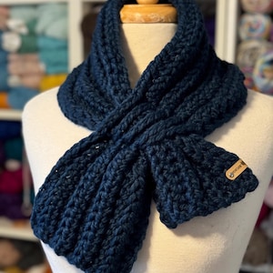 May include: A dark blue crocheted infinity scarf with a brown leather tag that says "handmade".