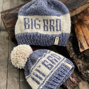 Puede incluir: Dos gorros de punto con pompones. El gorro m&aacute;s grande es azul y blanco con el texto "BIG BRO" en blanco. El gorro m&aacute;s peque&ntilde;o es azul y blanco con el texto "LITTLE BRO" en blanco.