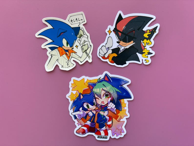 May include: Set of three stickers featuring Sonic the Hedgehog and Shadow the Hedgehog in various poses. One sticker shows Sonic on the phone with Japanese text. Another shows Shadow giving a thumbs up. The third sticker shows Sonic with another character.