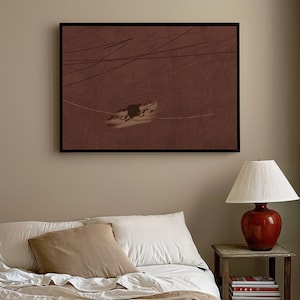 K&ouml;nnte beinhalten: Abstrakter Kunstdruck in einem schwarzen Rahmen. Das Kunstwerk zeigt einen weinroten Hintergrund mit wei&szlig;en und schwarzen Linien und einer zentralen, strukturierten Form. Der Druck h&auml;ngt &uuml;ber einem Bett mit wei&szlig;er Bettw&auml;sche und einem beigen Kissen. Eine rote Lampe steht auf einem h&ouml;lzernen Beistelltisch.