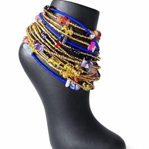 Peut inclure: Un bracelet de cheville multi-rangs composé de nombreuses perles de rocaille dorées entremêlées de petites pierres gemmes polies et irrégulières dans des tons bleu, jaune, violet, rouge et blanc, avec deux rangs de perles bleu roi.