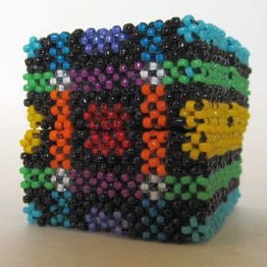May include: A small, colorful beaded box with a geometric pattern. The box is made of black, white, red, orange, yellow, green, blue, and purple beads.