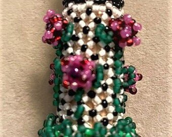 Puede incluir: Un diseño de flores de cuentas con cuentas rosas, verdes y rojas. Las cuentas están dispuestas en un patrón que se asemeja a un tallo de flor con hojas y flores.