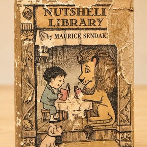 May include: Vintage "Nutshell Library" book by Maurice Sendak. The cover features an illustration of a boy and a lion reading at a table, with a small dog. The book is tan with wear and tear.