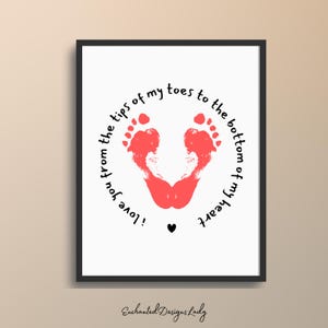 May include: Framed print featuring two red foot imprints forming a heart shape. The text "I love you from the tips of my toes to the bottom of my heart" is written in a circular pattern around the footprints. A small black heart is below the footprints.