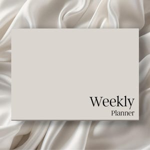 May include: A rectangular weekly planner with a solid light beige cover. The text Weekly Planner is printed in a black serif font in the bottom right corner of the cover. The planner has a clean, flat surface and a simple, professional design.