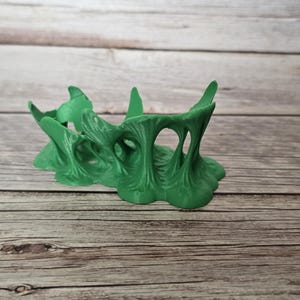 Può includere: Tre oggetti decorativi astratti azzurri. Gli oggetti hanno un design fluido e organico, con forme arrotondate e una consistenza liscia. Sono disposti su una superficie di legno.