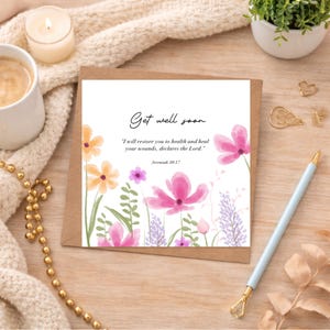 Peut inclure: Une carte carrée de vœux « Get well soon » avec un motif floral. La carte présente des fleurs à l'aquarelle dans les tons rose, orange et violet. Le texte dit : « Je te rétablirai la santé et je guérirai tes blessures, déclare le Seigneur. » Jérémie 30:17 est également inclus.