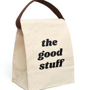 Off white canvas lunch bag with brown handle. Very simple. On the front in black retro lower case font it says "the good stuff". Great gift for loved one or for yourself for a fun lunch box.