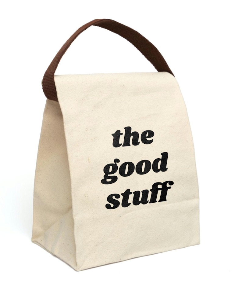 Off white canvas lunch bag with brown handle. Very simple. On the front in black retro lower case font it says "the good stuff". Great gift for loved one or for yourself for a fun lunch box.