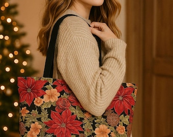 Op de afbeelding: Een zwarte tote bag met een levendig bloemenpatroon van rode kerststerren, oranje bloesems en bruine dennenappels. De tas heeft stevige zwarte schouderbanden en een rechthoekige vorm, voorzien van een gedetailleerde botanische print.