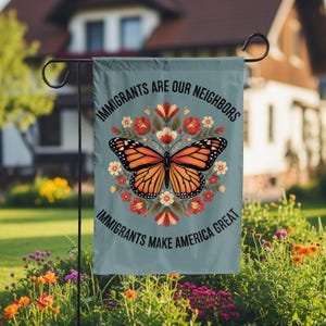 May include: A rectangular garden flag with a light blue background featuring a central orange and black monarch butterfly surrounded by a circular floral pattern. The text reads IMMIGRANTS ARE OUR NEIGHBORS and IMMIGRANTS MAKE AMERICA GREAT.