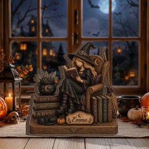 Peut inclure: Une figurine décorative représentant une sorcière aux longs cheveux portant un chapeau pointu, assise dans un fauteuil en bois en train de lire. La base comprend une pile de livres marqués "JUST A GIRL WHO LOVES BOOKS", un chaudron, un chat noir et une plaque "Emma".