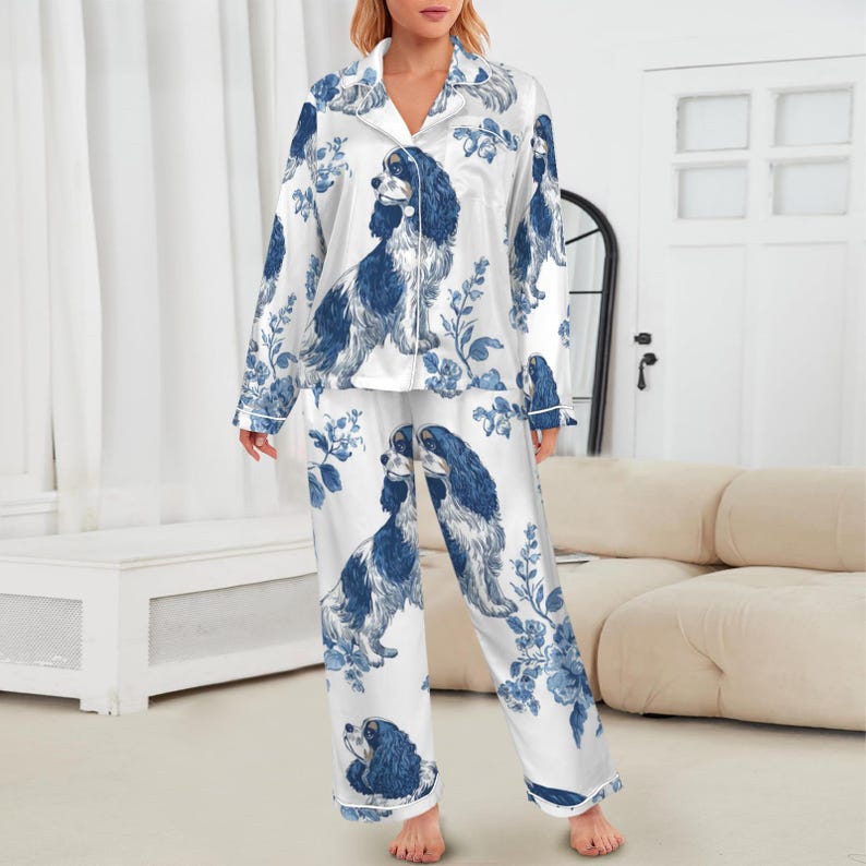 Puede incluir: Conjunto de pijama de sat&eacute;n blanco con un estampado floral y de perro azul y blanco. La parte superior de manga larga tiene una parte delantera abotonada y los pantalones tienen un corte holgado. El conjunto de pijama es una opci&oacute;n de ropa de dormir c&oacute;moda.