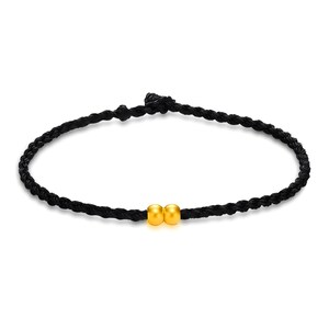 May include: A black braided bracelet featuring two small, round, gold-colored beads. The bracelet is made of a dark, possibly nylon, cord. The beads are centered on the bracelet.