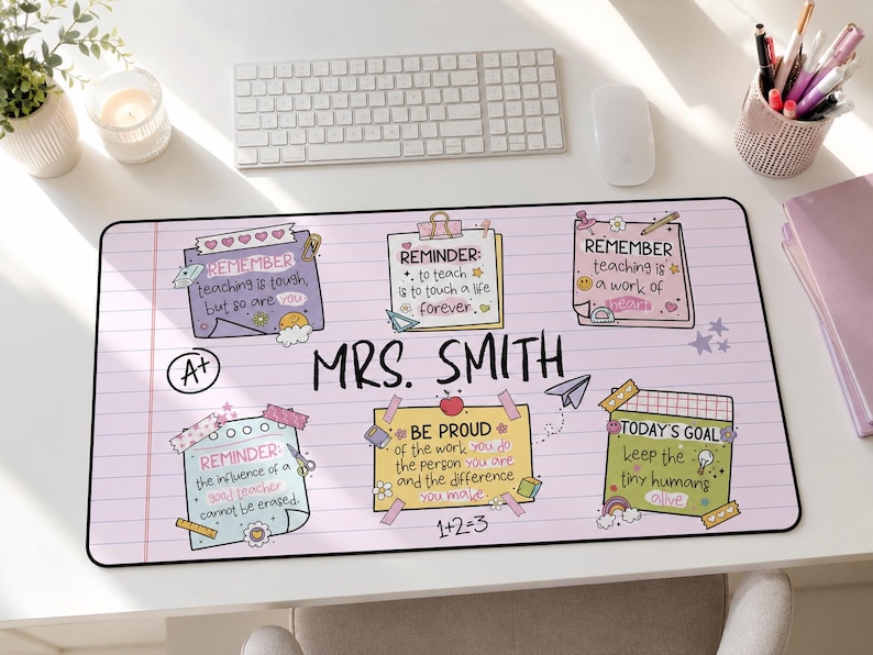 以下が含まれることがあります： 中央に「MRS. SMITH」という文字が書かれた、薄紫色の罫線入り紙風の長方形デスクマット。教師向けの感動的な引用が書かれた6枚のカラフルな付箋風グラフィック、A+の評価アイコン、紙飛行機や数式などの小さな落書きが描かれています。