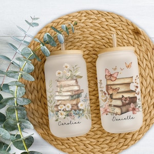 May include: Two frosted glass tumblers with bamboo lids and straws. One features a stack of books with daisies and the name Caroline. The other shows a stack of books with butterflies and the name Danielle. Both have botanical accents.