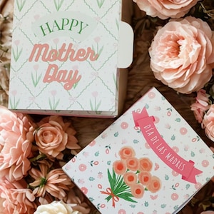 Puede incluir: Dos tarjetas decorativas del Día de la Madre con diseños florales y las frases "Happy Mother's Day" y "Día de las Madres". Las tarjetas están rodeadas de rosas rosas, creando una estética suave y femenina.
