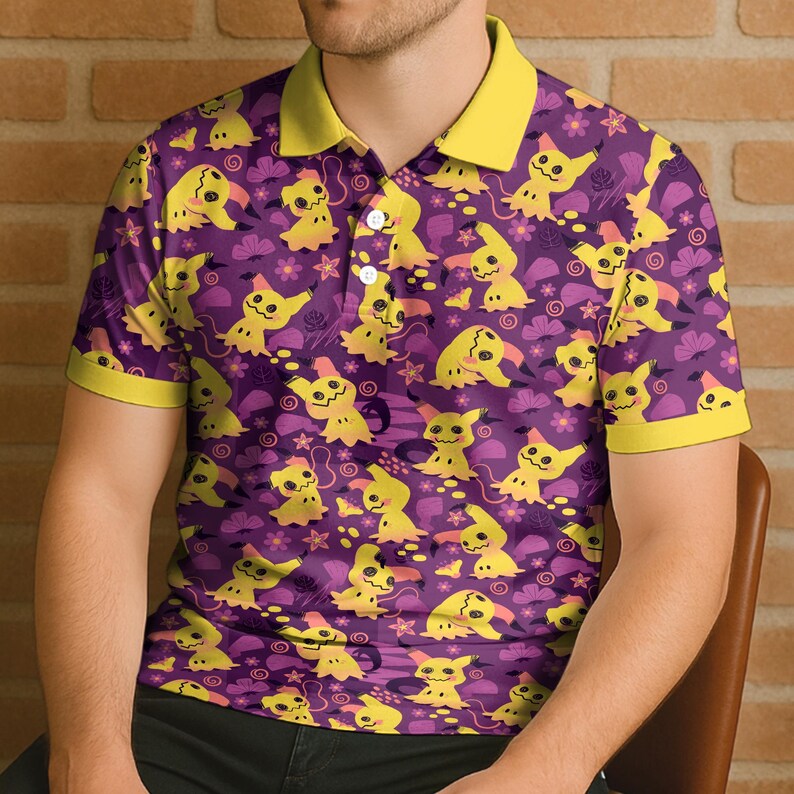 May include: Purple polo shirt featuring a repeating pattern of yellow cartoon characters, flowers, and swirls. The collar and sleeve cuffs are yellow. The shirt has a three-button placket.