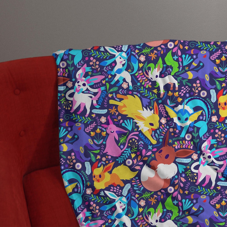 May include: A soft throw blanket featuring a dark blue background with a repeating pattern of various colorful cartoon creatures, including yellow, pink, brown, and blue characters, interspersed with vibrant green leaves and small flowers.