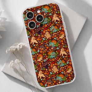 May include: A clear smartphone case featuring a repeating pattern of cartoon creatures, orange pumpkins, sunflowers, and small stars against a dark brown background. The design includes the text BOO! scattered among the various illustrated elements.