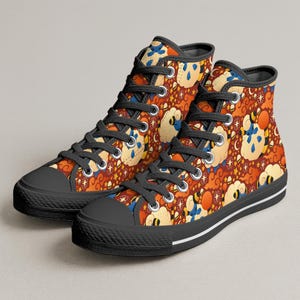 May include: Pair of high-top canvas trainers featuring a colourful pattern of cartoon sheep, clouds, and stars on a reddish-brown background. The trainers have black laces, toe caps, and soles, with a white stripe along the sole.