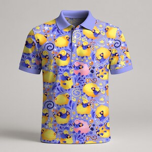 May include: A short-sleeved polo shirt with a whimsical pattern of yellow and pink sheep on a lavender background. The shirt has a light purple collar and sleeve cuffs. The sheep are decorated with blue accents and surrounded by stars and floral elements.
