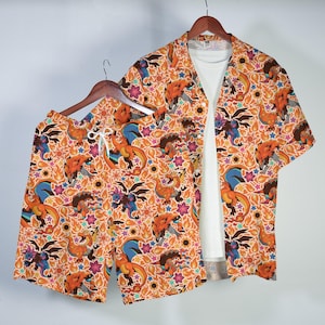 May include: A short-sleeve button-down shirt and matching shorts set featuring an all-over print of orange, blue, and black dragon-like creatures, yellow flames, and small colorful stars on an orange background, layered over a plain white t-shirt.