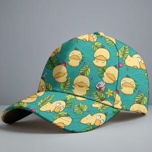 Puede incluir: Una gorra de béisbol con un fondo turquesa que presenta un patrón repetido de patos amarillos de dibujos animados, hojas verdes y pequeñas bayas azules. La gorra tiene una visera curva y una parte superior amarilla.