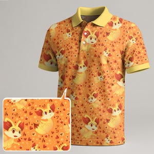 May include: Orange polo shirt featuring a repeating pattern of a cartoon fox-like creature, hearts, and Japanese text. The shirt has a yellow collar and sleeve cuffs. The design is printed on the entire shirt.